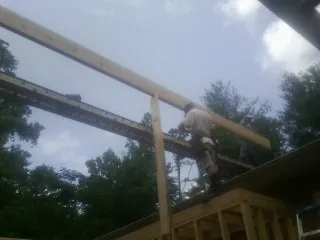 Carpenter setting a ridge beam over a new addition frame — Ice Dam Removal by Roofing Brothers in Petersham