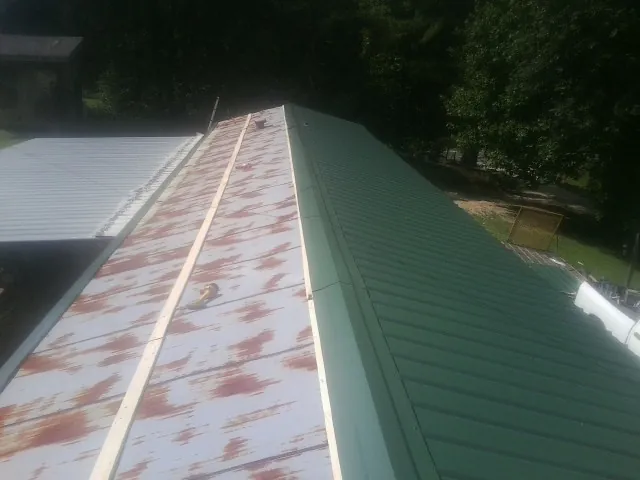 Old rusted panels beside newly installed green metal roofing — Wind Damage Roof Repair by Roofing Brothers in Petersham