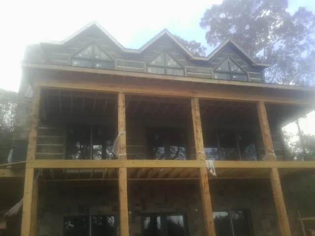 Dormers and porch framing on a large log home under construction — Roof Coating work by our crew in Petersham