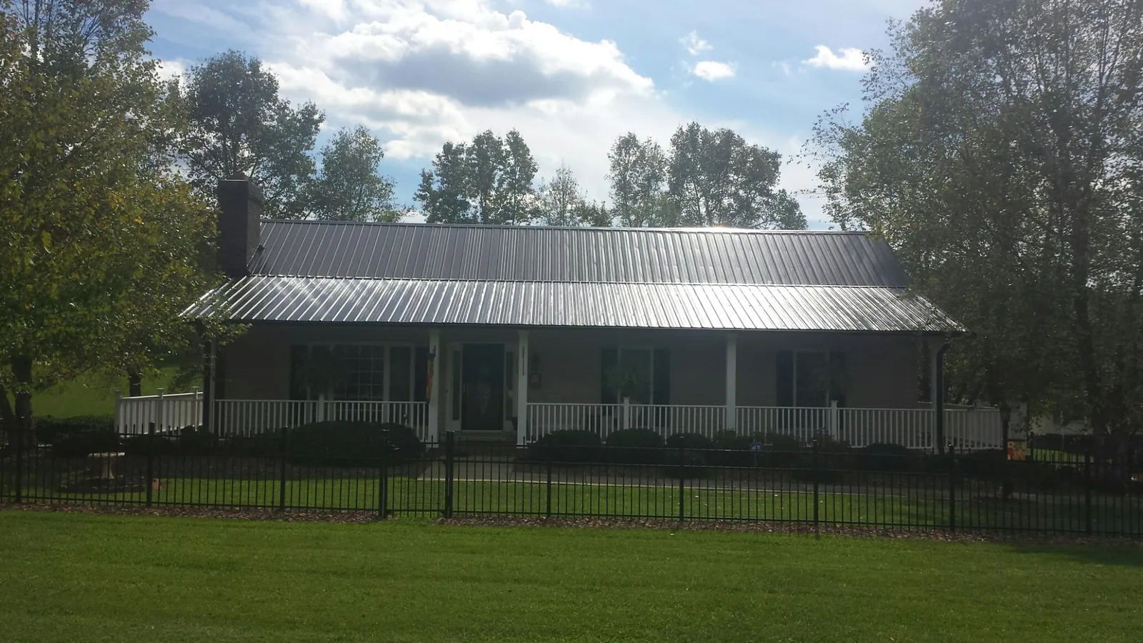 Gray metal roof on a brick ranch with a full width front porch — Gutter Guard Installation work by our crew in Petersham