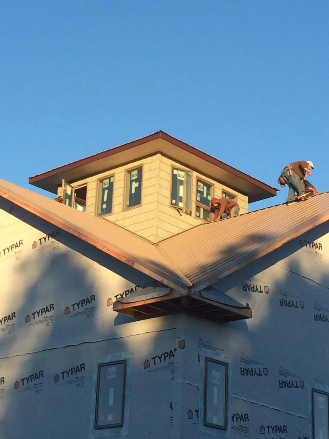 Roofers working around a rooftop cupola on a new metal roof at sunset — Roof Waterproofing in Petersham by Roofing Brothers
